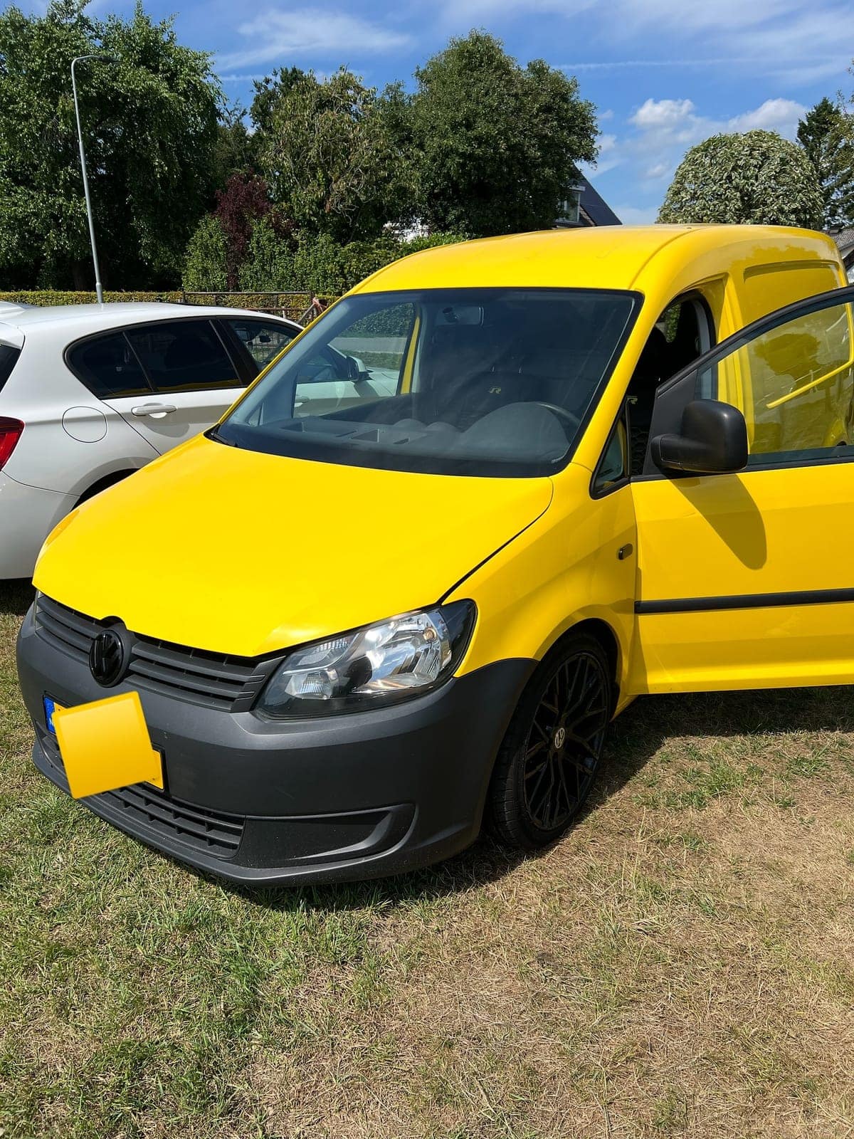 Gele Volkswagen Caddy van voren, met koplamp, grille en motorkap in beeld