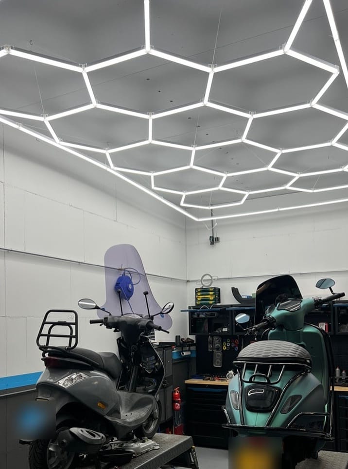 Nieuwe werkplaats met zeshoekige ledverlichting aan het plafond en twee scooters op de brug