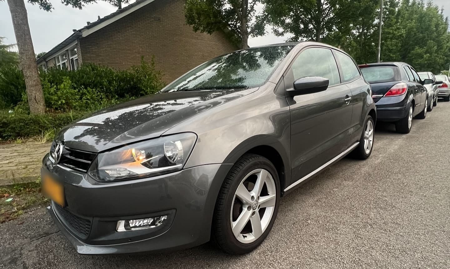 Grijze Volkswagen Polo uit 2013, van voren gezien langs de stoep