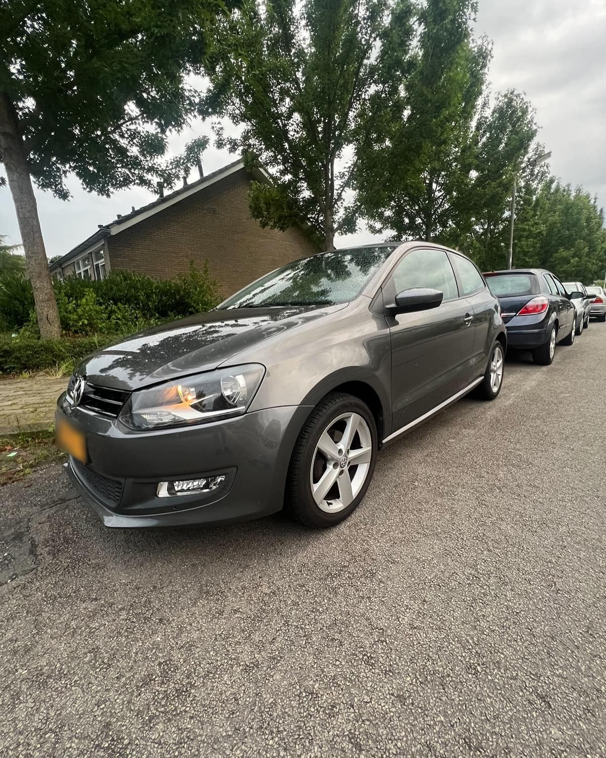 Grijze Volkswagen Polo langs de stoep