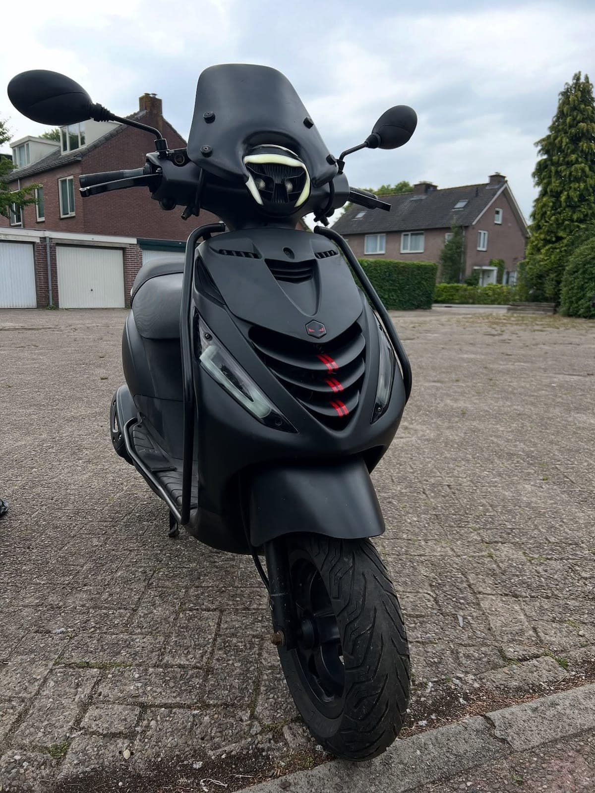 Matzwarte scooter van voren, met windscherm en koplamp